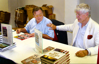 Joe Galloway gets a tap from fellow author Jim Brady while signing bookat the 2008 Combat Correspdents Conference in San Antonio.