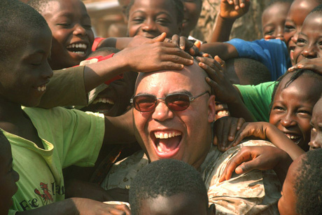 Maj. Jason P. Smith, convoy commander and amphibious assault officer, takes time away from convoy operations to interact and play with some Liberian children during a convoy to deliver humanitarian supplies throughout the city of Monrovia, Liberia.  